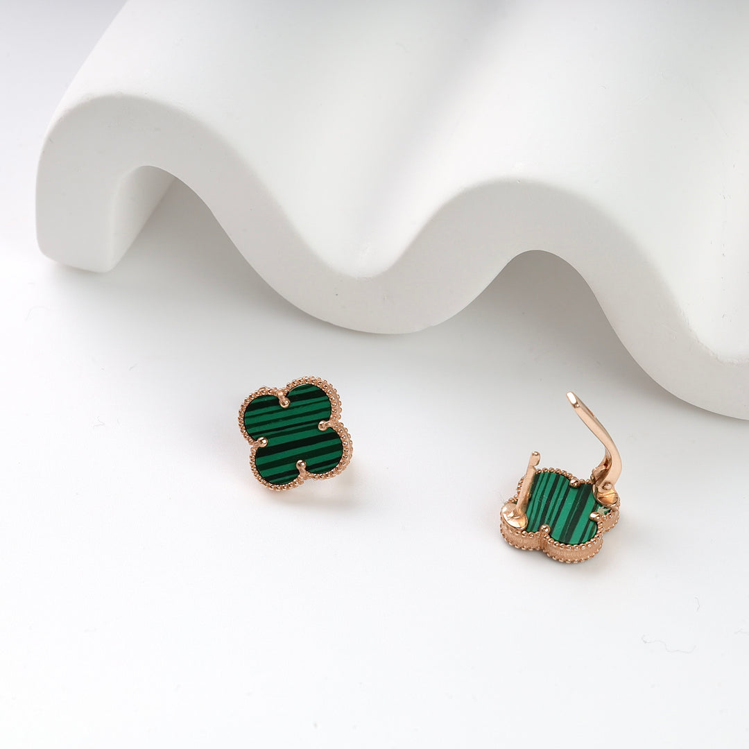 Pair of gold clover-shaped earrings with green malachite inlay displayed on a white surface.