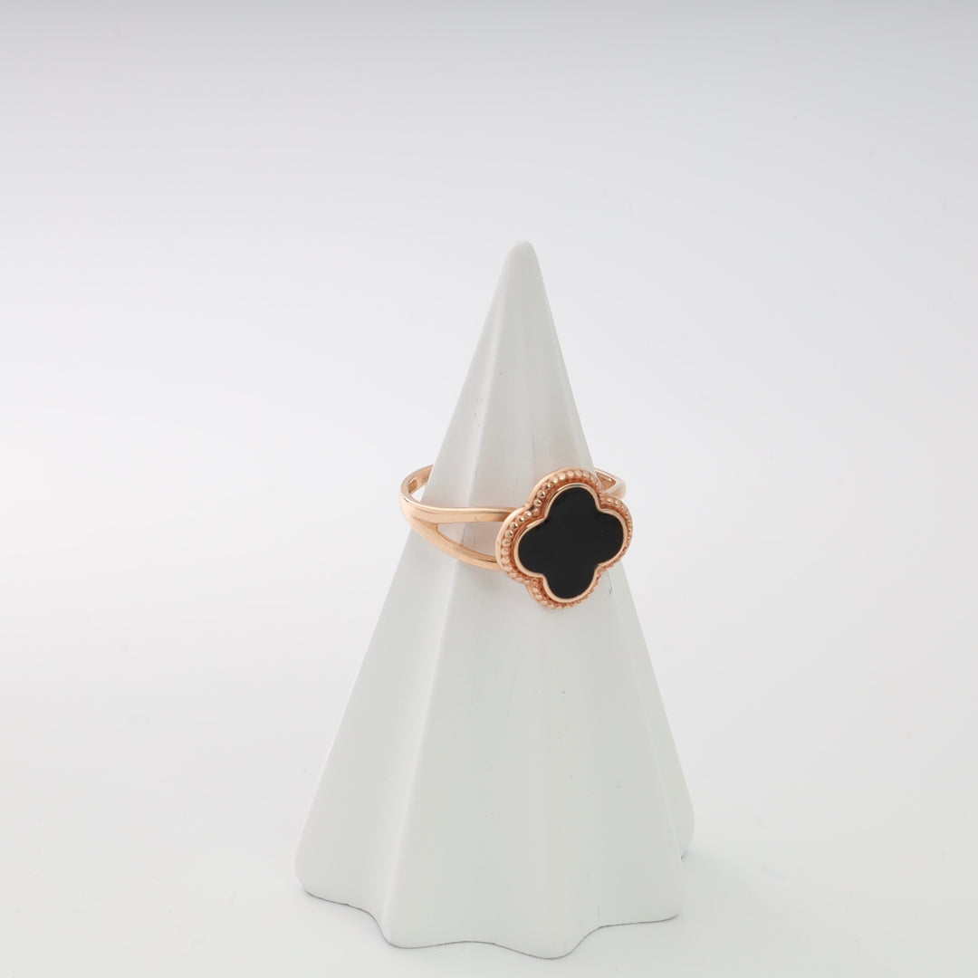Rose gold ring with black enamel quatrefoil design on a white display cone.