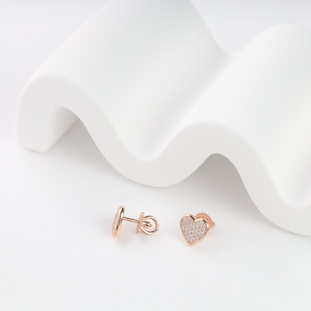 Rose gold heart stud earrings with clear gemstones on a white wave backdrop.