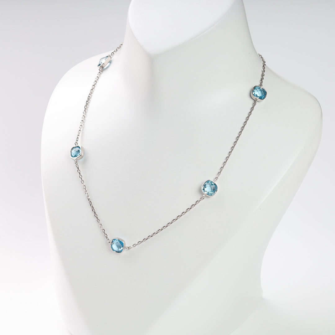 Silver necklace with blue gemstone stations on a white display.