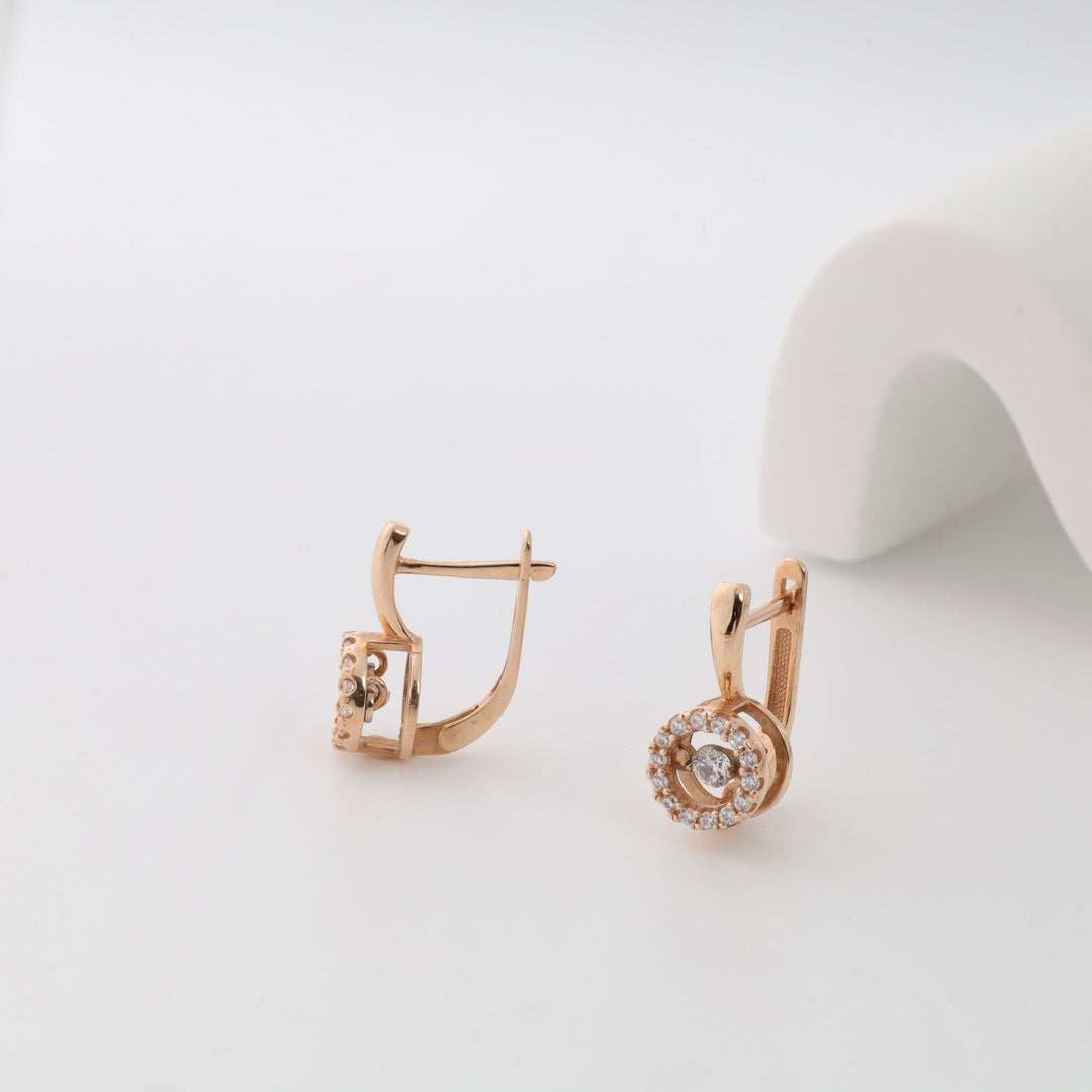 Rose gold earrings with diamond cluster and round design on white background.