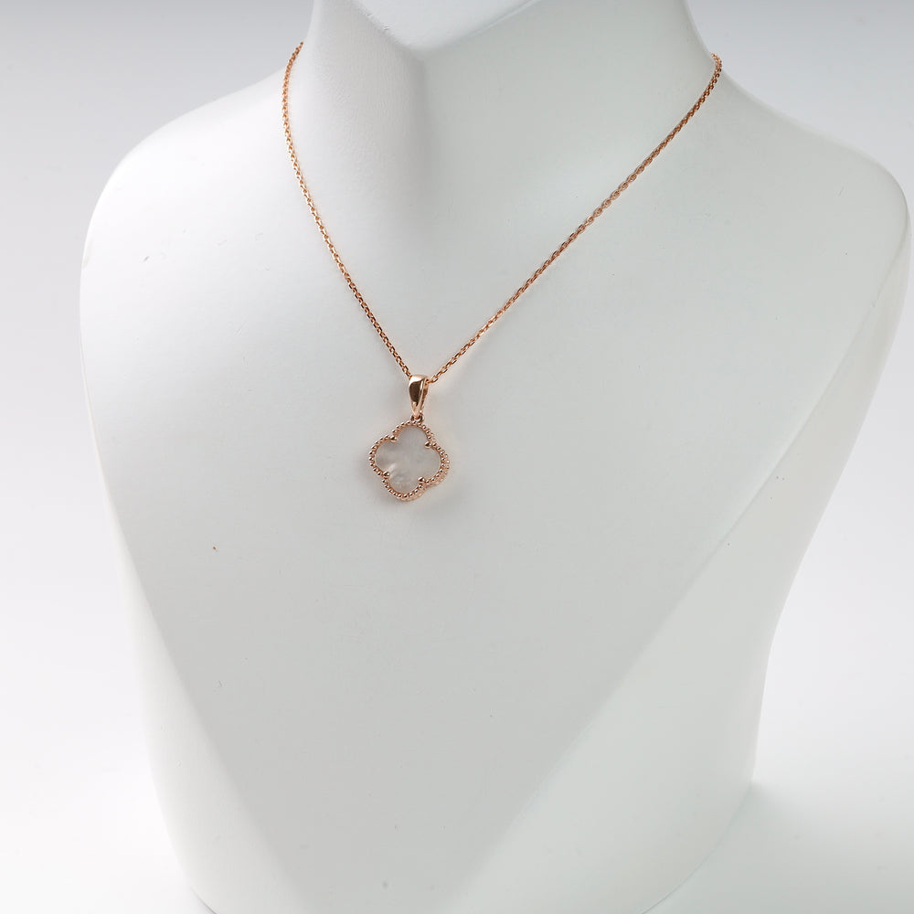 Gold chain necklace with a clover-shaped pendant and white center displayed on a white bust. Gold clover necklace.