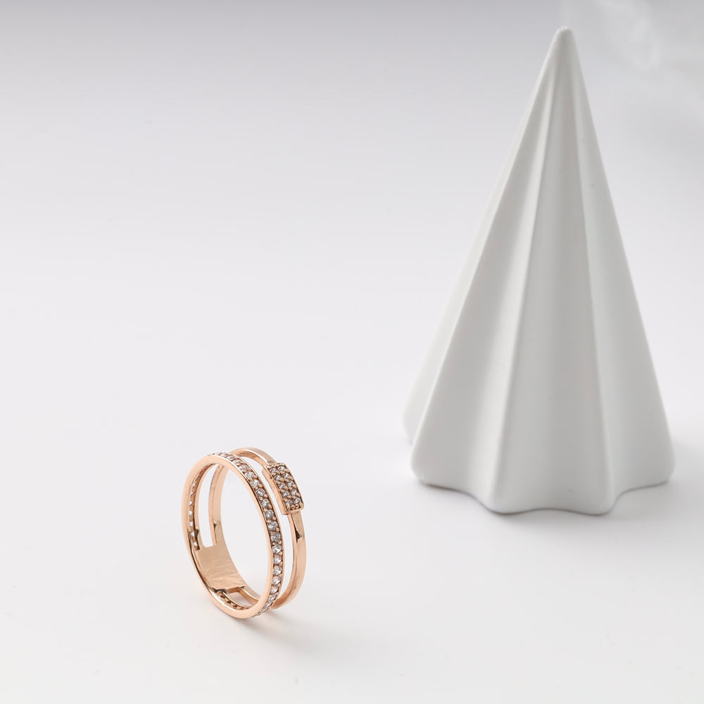 Rose gold double band ring with cubic zirconia detail on a white surface.