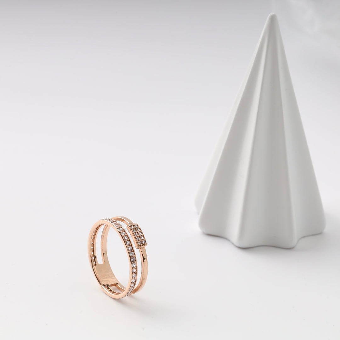 Rose gold double band ring with cubic zirconia detail on a white surface.