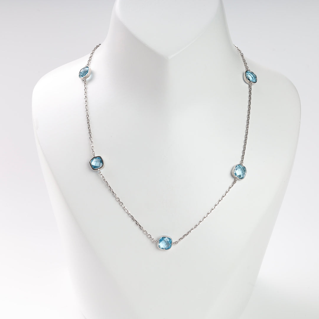 Silver necklace with five blue gemstone charms on a mannequin display.