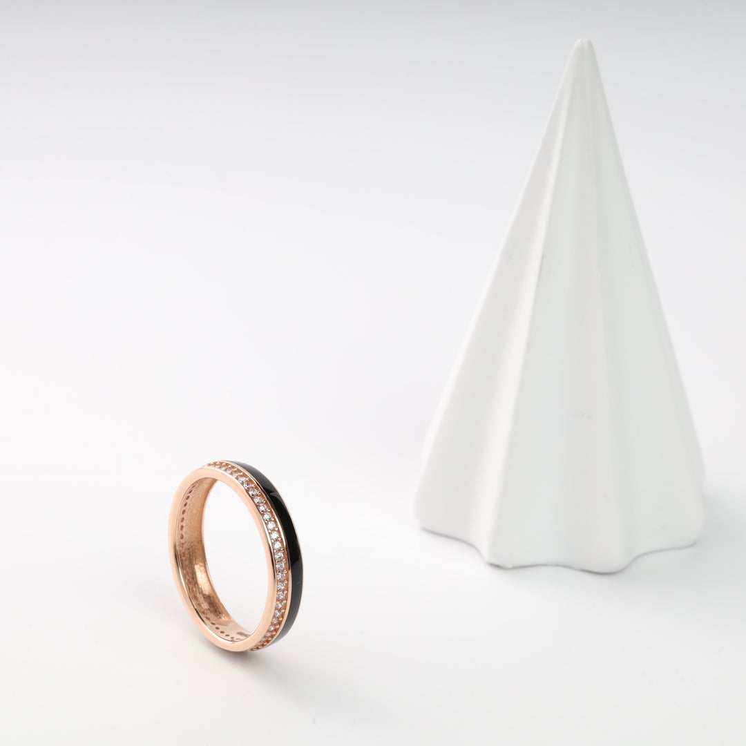 Rose gold and black ring with cubic zirconia accents displayed on a white surface.
