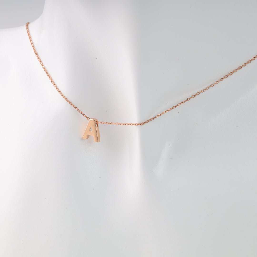 Rose gold necklace with letter A pendant on mannequin bust.