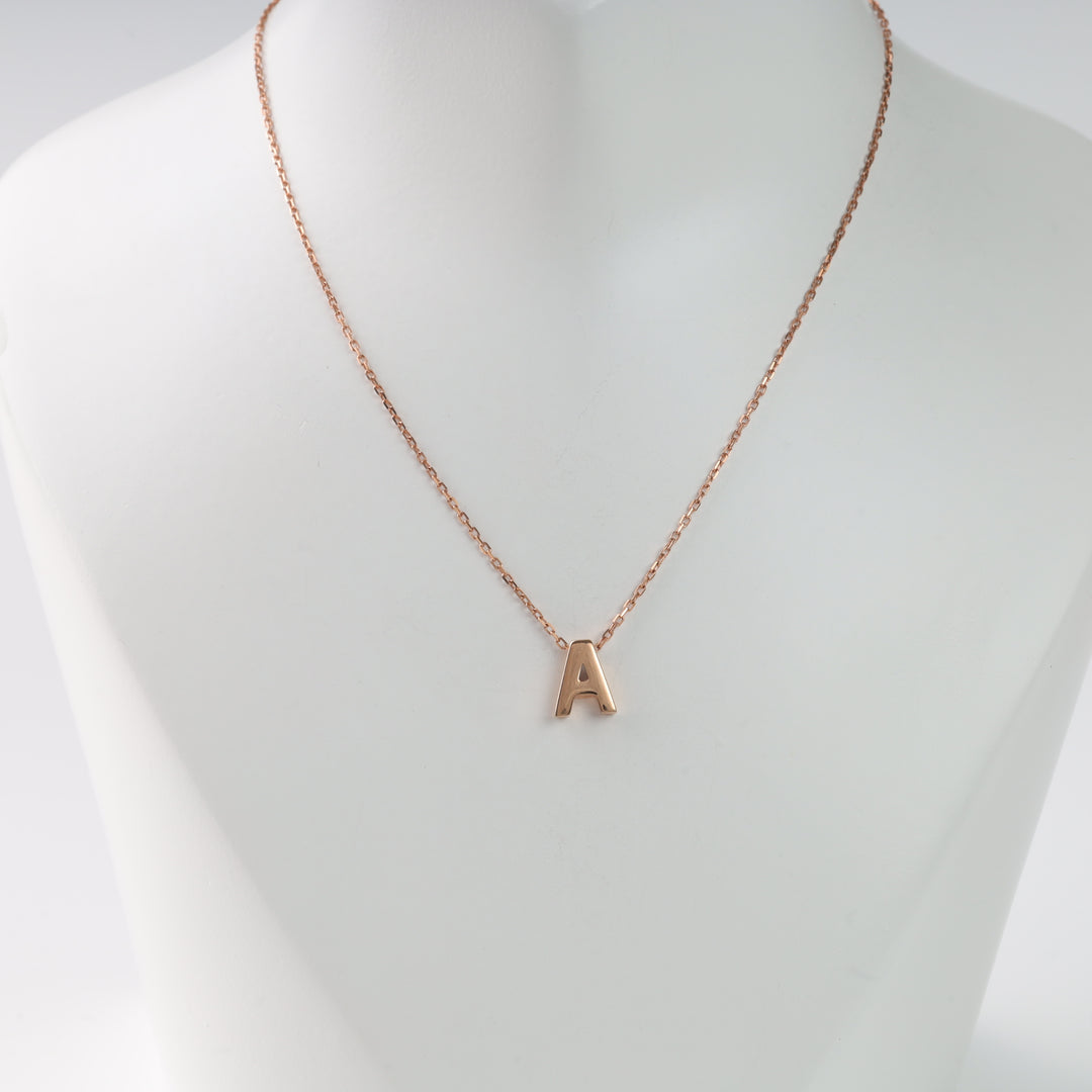 Rose gold necklace with "A" pendant on white display. Alphabet charm jewelry.