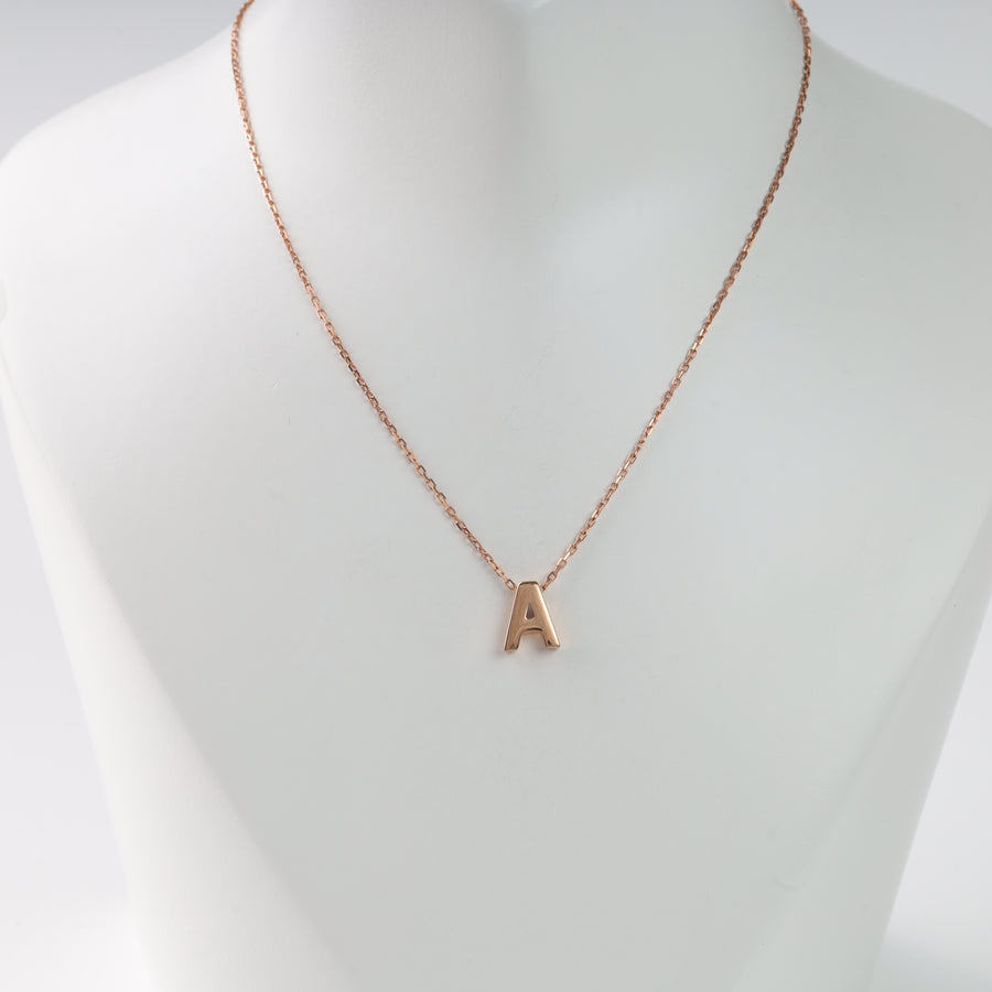 Rose gold necklace with "A" pendant on white display. Alphabet charm jewelry.
