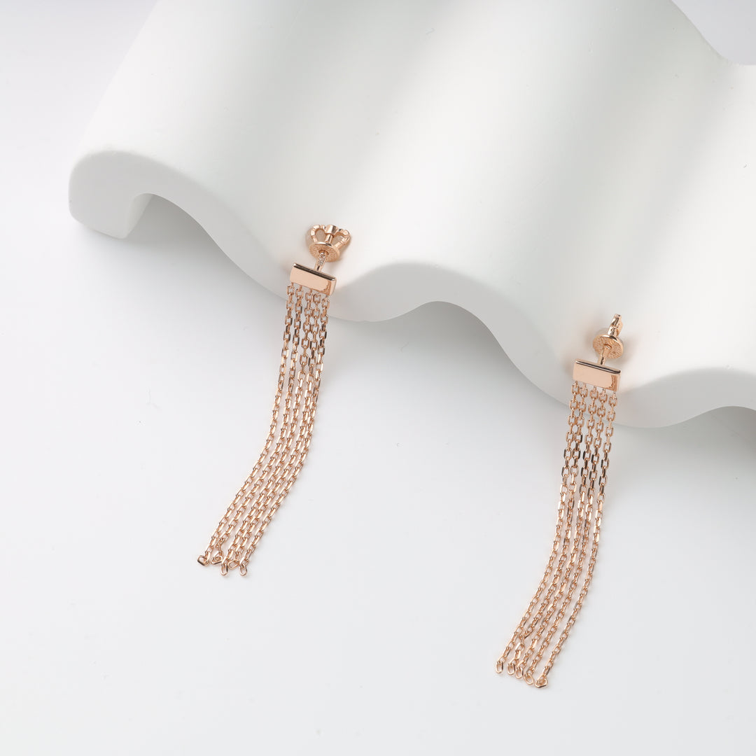 Pair of rose gold chain tassel drop earrings on a white wavy display, rose gold tassel earrings, chain drop earrings.