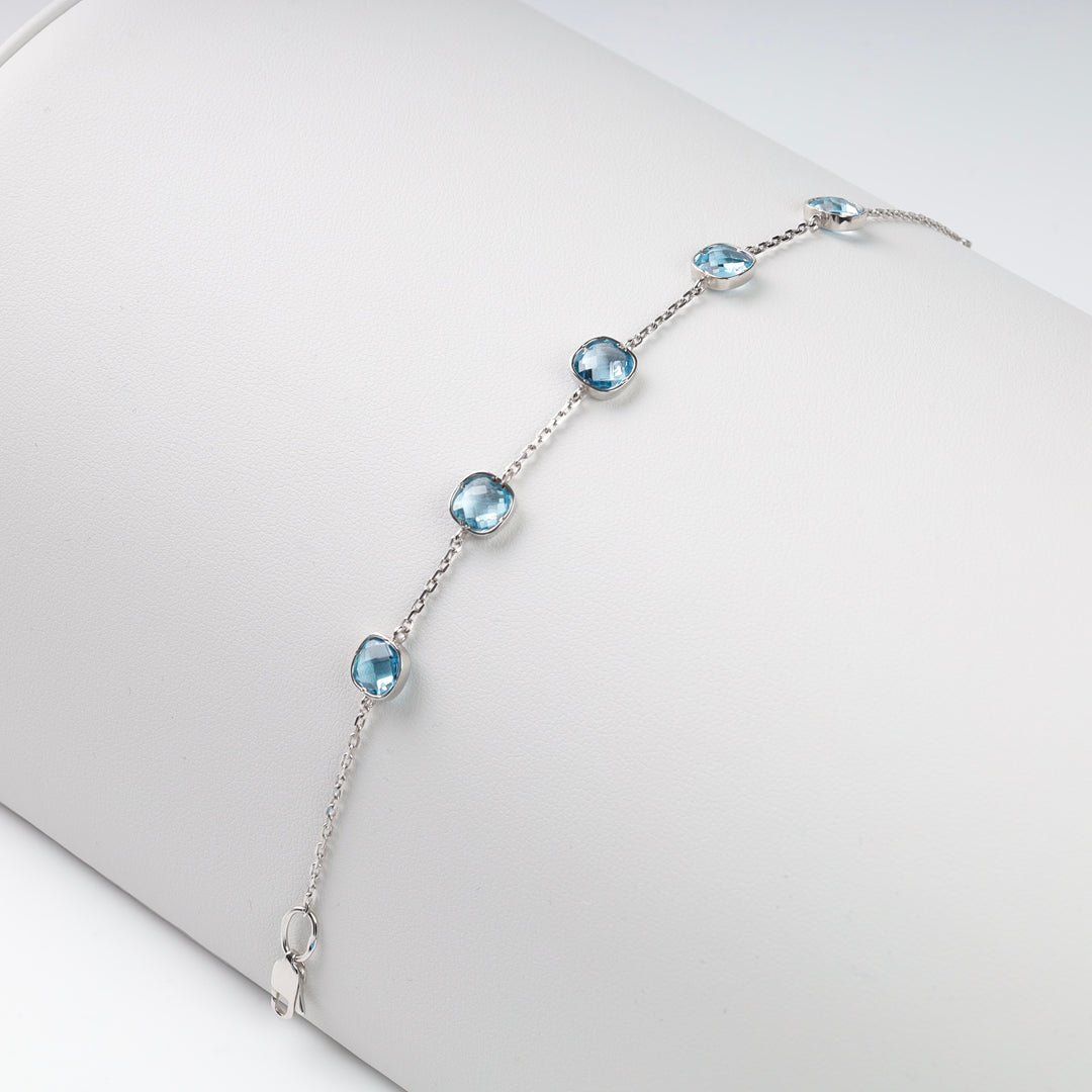 Silver bracelet with round blue gemstones on a white background.
