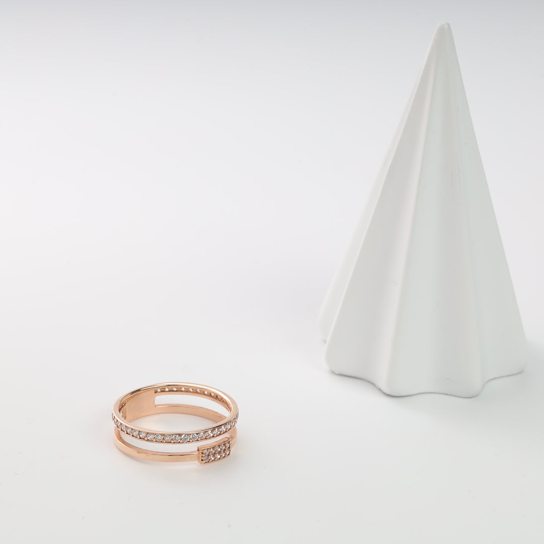 Rose gold double band ring with cubic zirconia stones on a white pyramid stand.