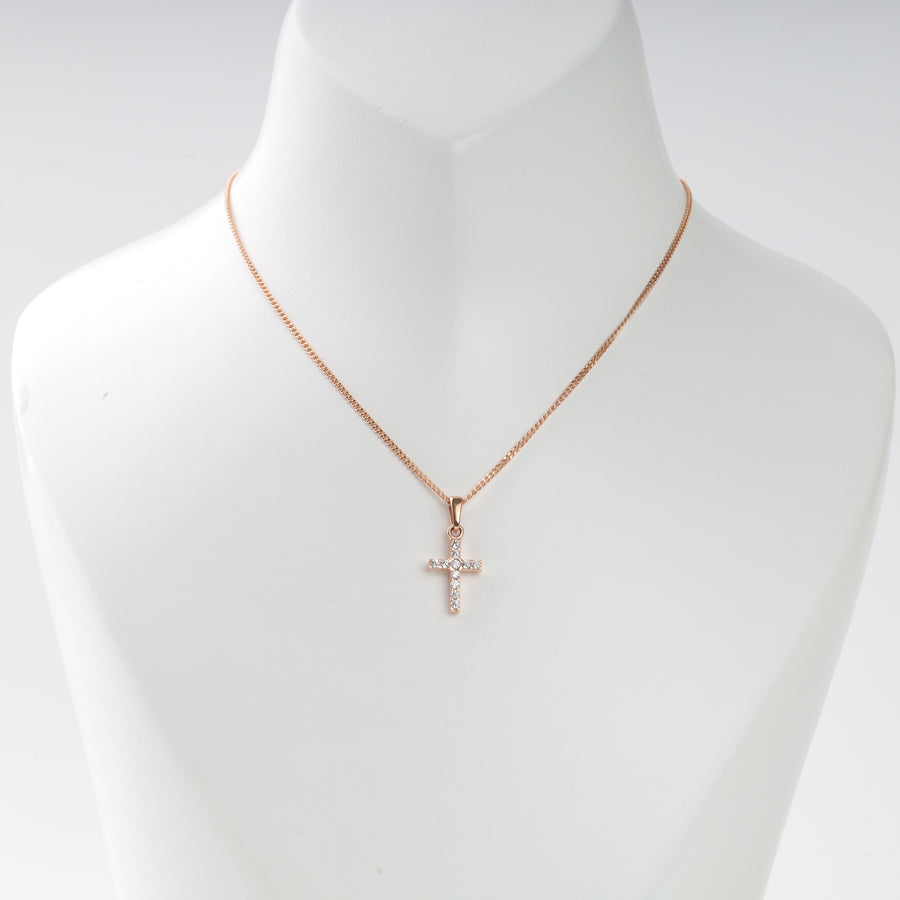 Rose gold necklace with a small cross pendant set with clear stones, displayed on a white bust. Cross necklace jewelry.