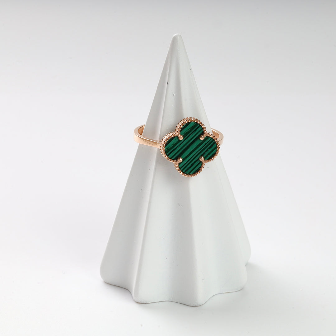 Gold ring with a green malachite clover-shaped motif displayed on a white ring stand.