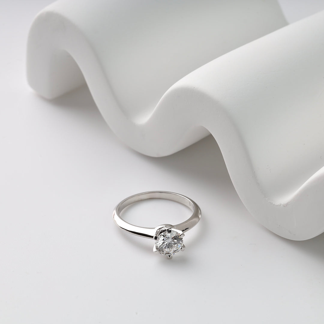 White gold  ring with a diamond on a white fabric background
