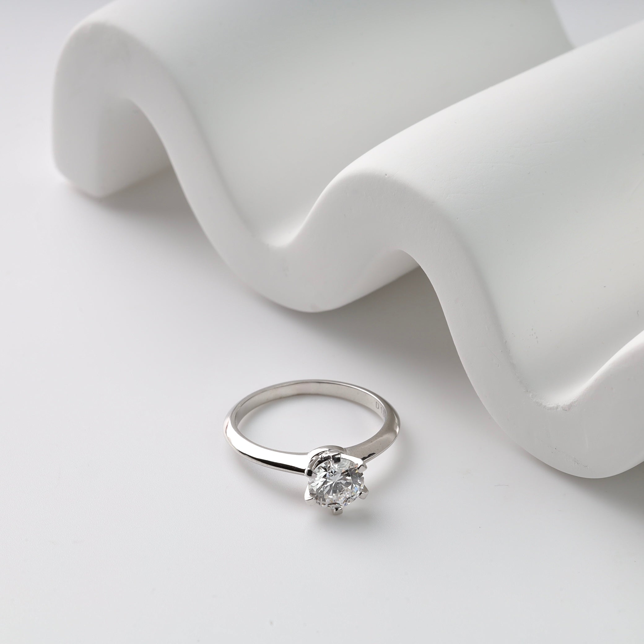 White gold  ring with a diamond on a white fabric background