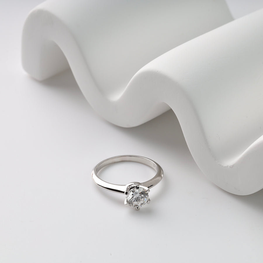 White gold  ring with a diamond on a white fabric background