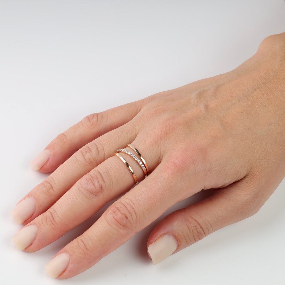 Two rose gold rings on a woman's hand, one plain and one with small diamonds.