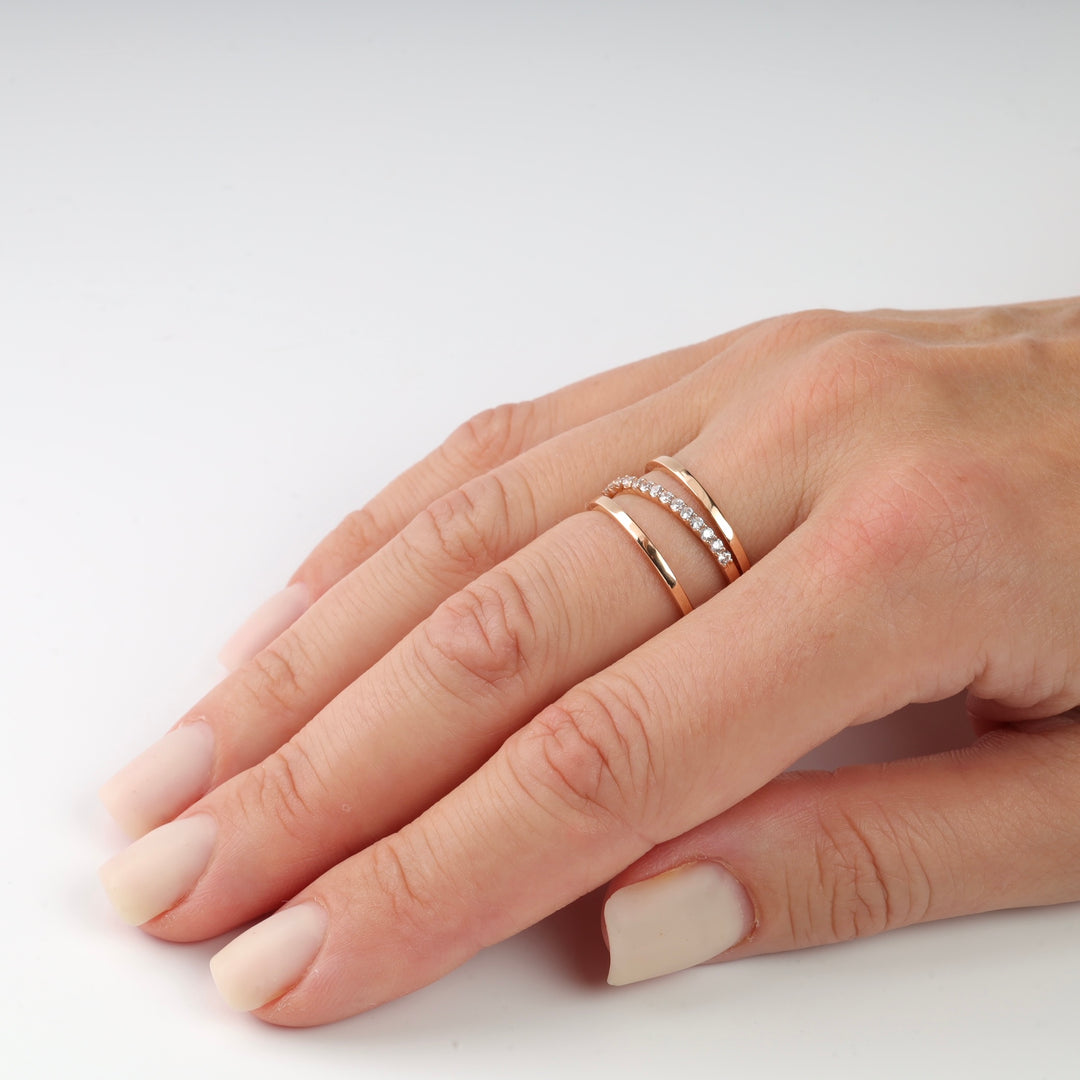 Rose gold rings with diamonds on a finger with natural nails.