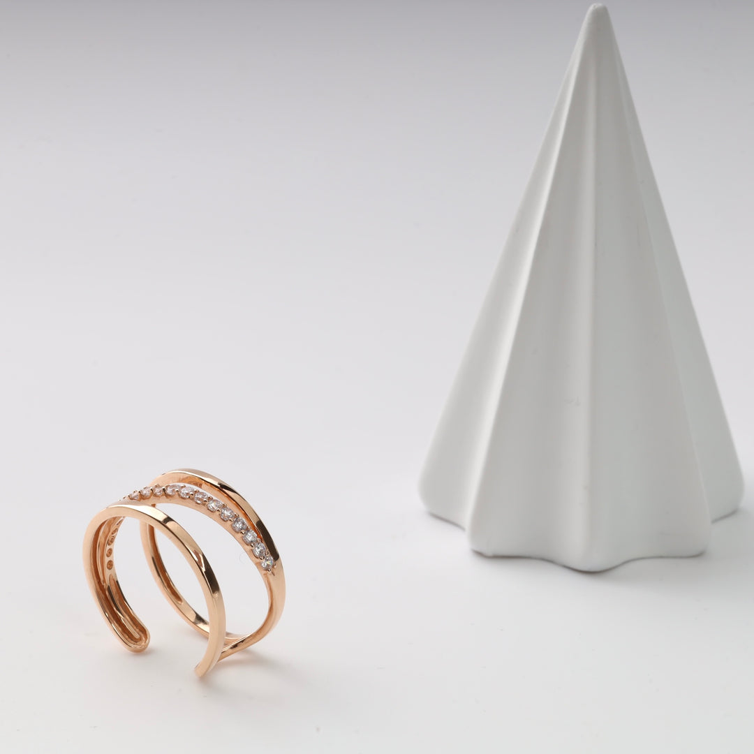 Gold double band ring with small diamonds, displayed next to a white geometric cone.