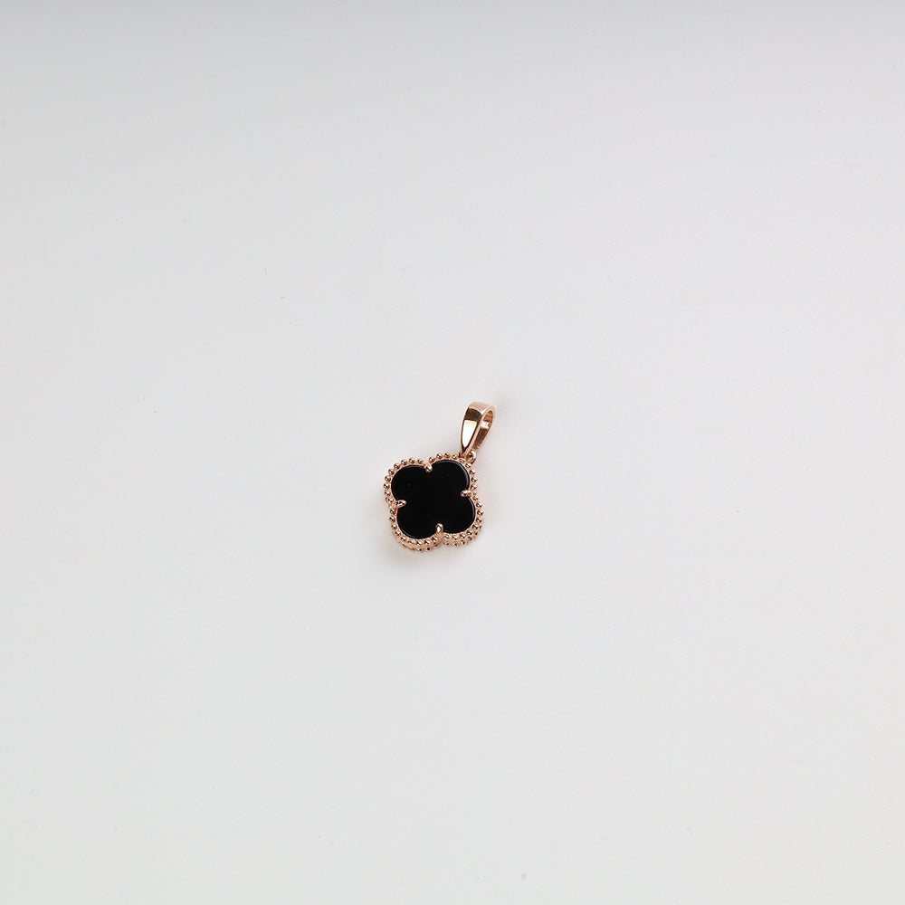 Gold clover pendant with black enamel center on a white background, jewelry charm, gold necklace pendant.
