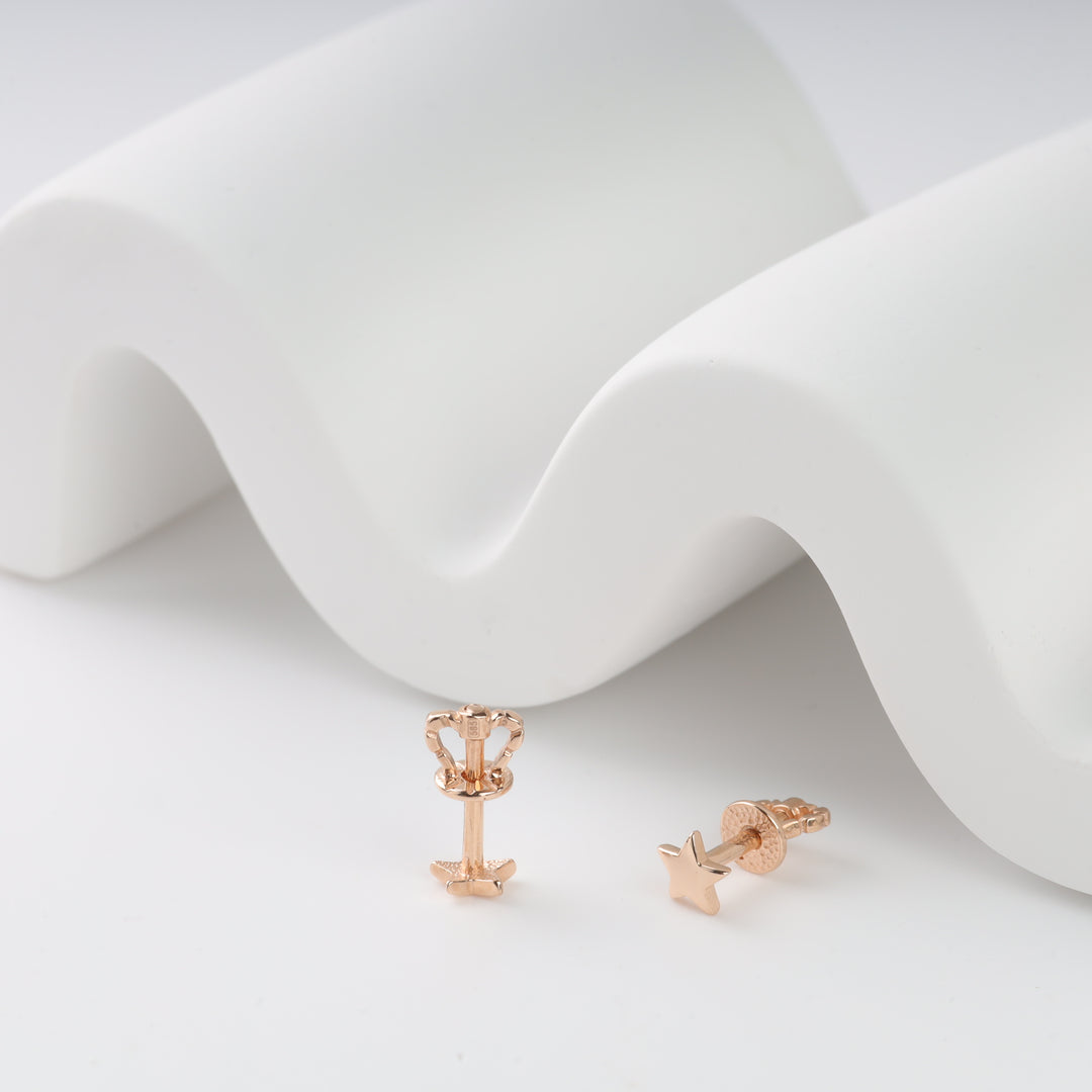 Rose gold star stud earrings displayed on a white wave surface.