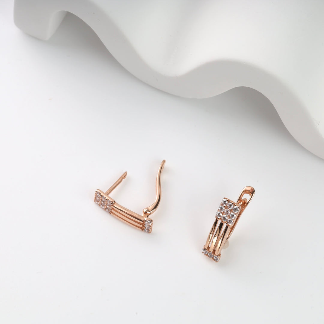 Rose gold hoop earrings with cubic zirconia detail on white background.