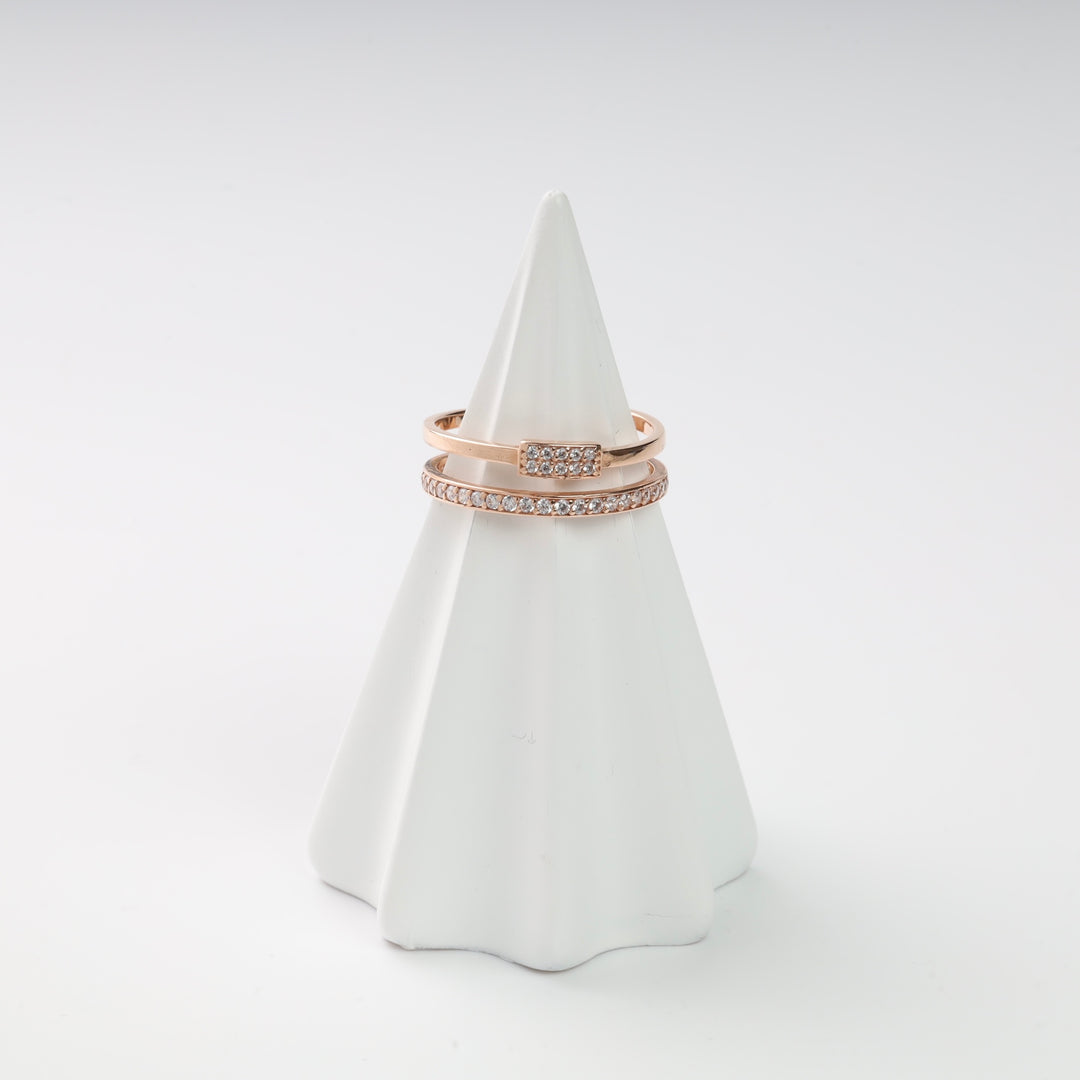 Rose gold rings with small diamonds displayed on a white cone.