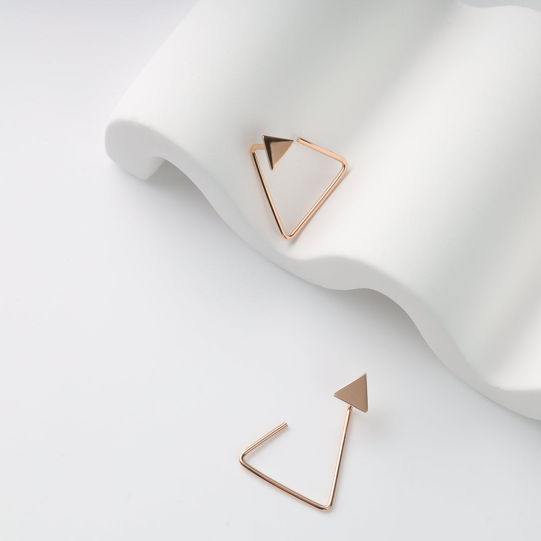 Pair of rose gold triangle hoop earrings with solid triangle studs on a white sculpted prop, geometric earrings.