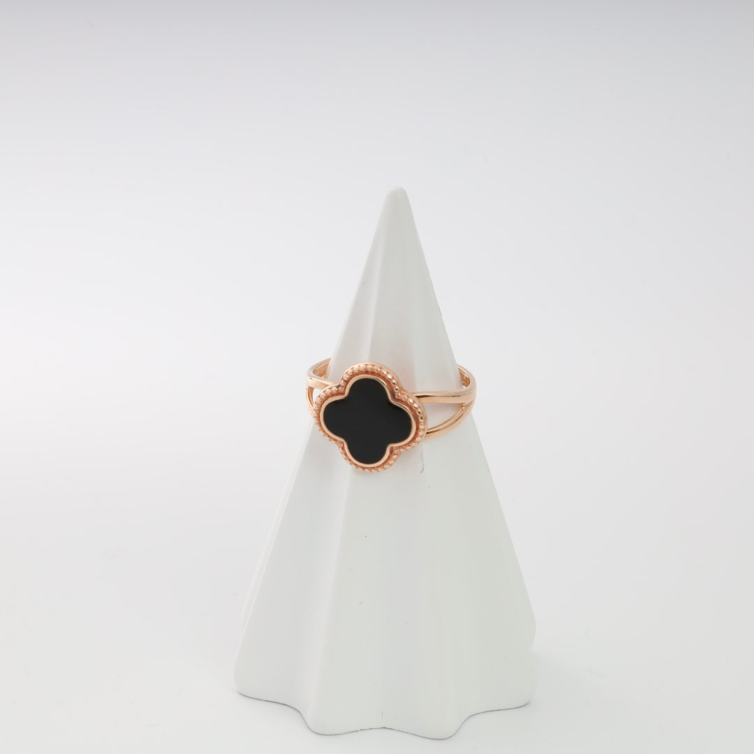 Rose gold ring with black quatrefoil design displayed on a white cone.