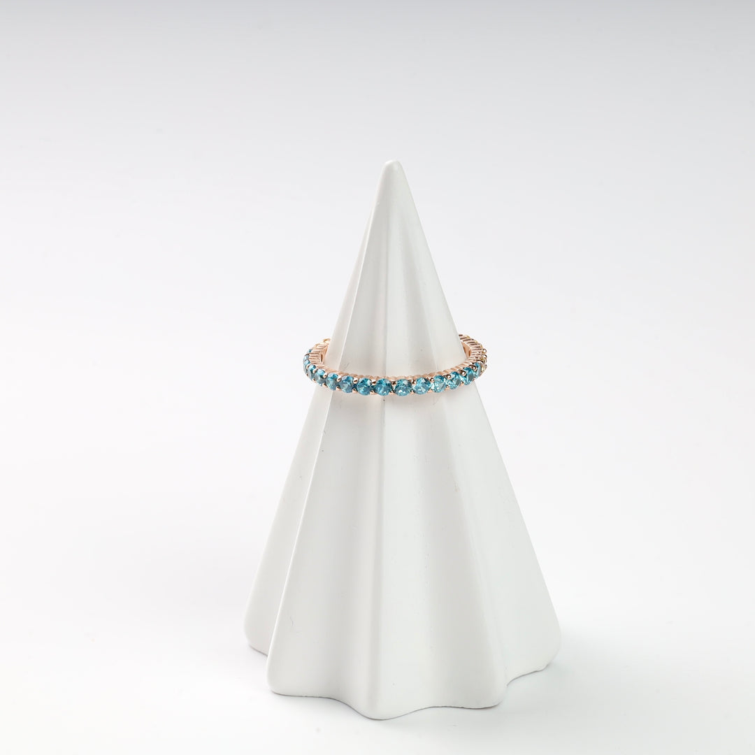 Gold ring with blue gemstones displayed on a white cone stand.