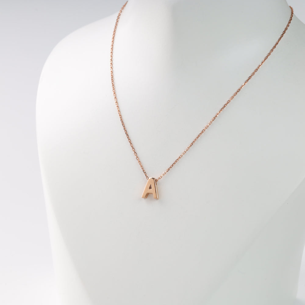Rose gold necklace with a letter "A" charm on a white bust. Elegant initial jewelry.