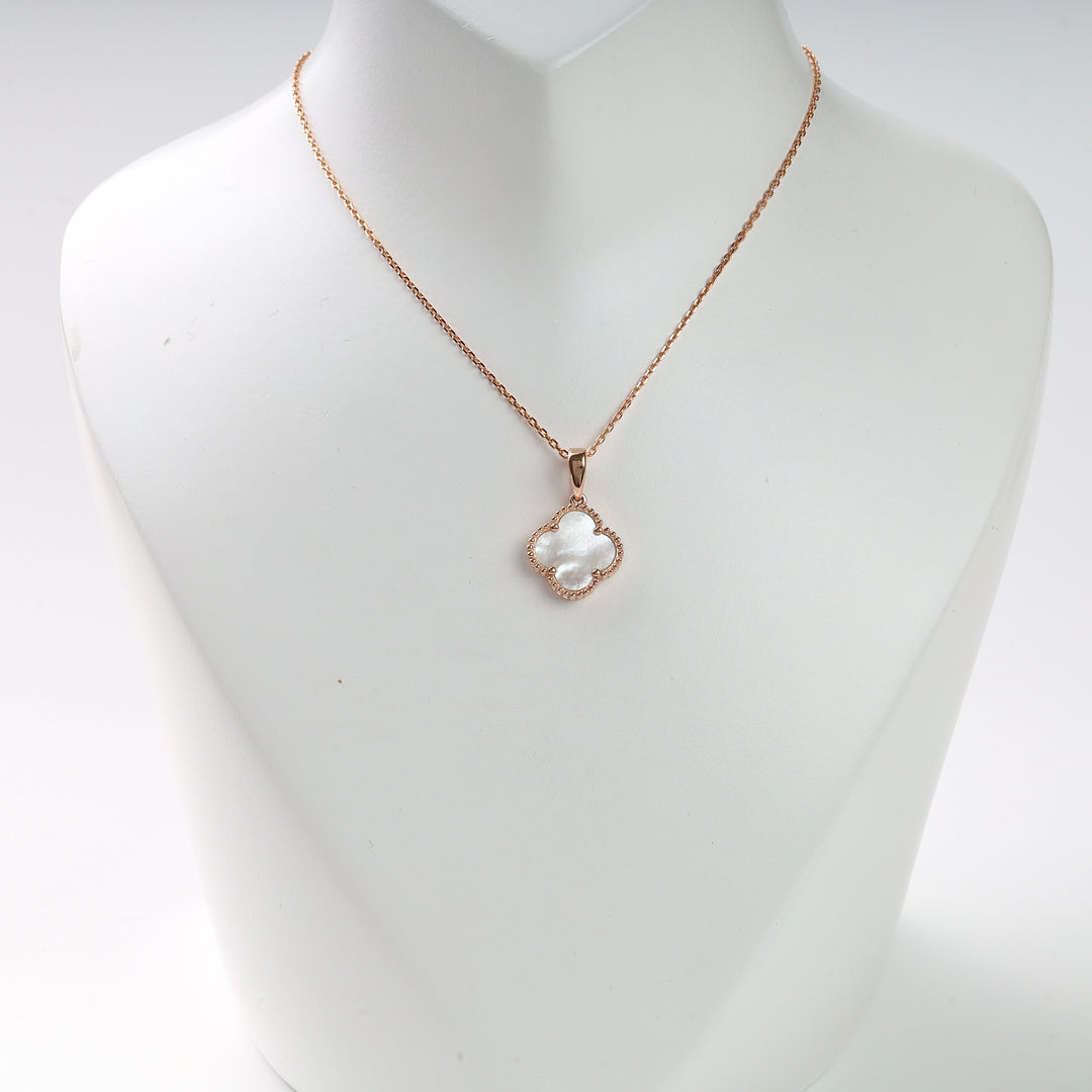 Gold chain necklace with a white mother of pearl clover pendant displayed on a white bust.
