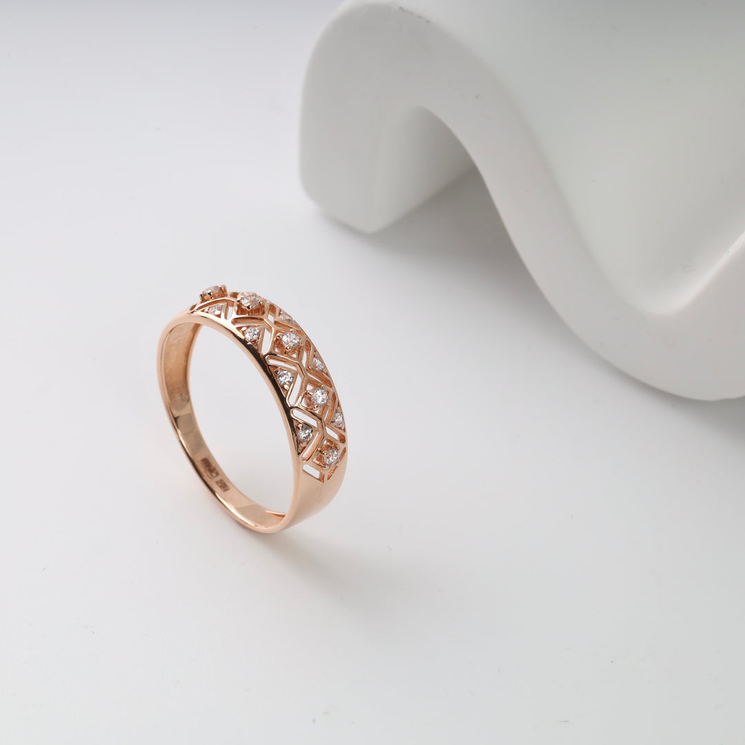 Rose gold ring with diamond lattice design displayed on white surface.