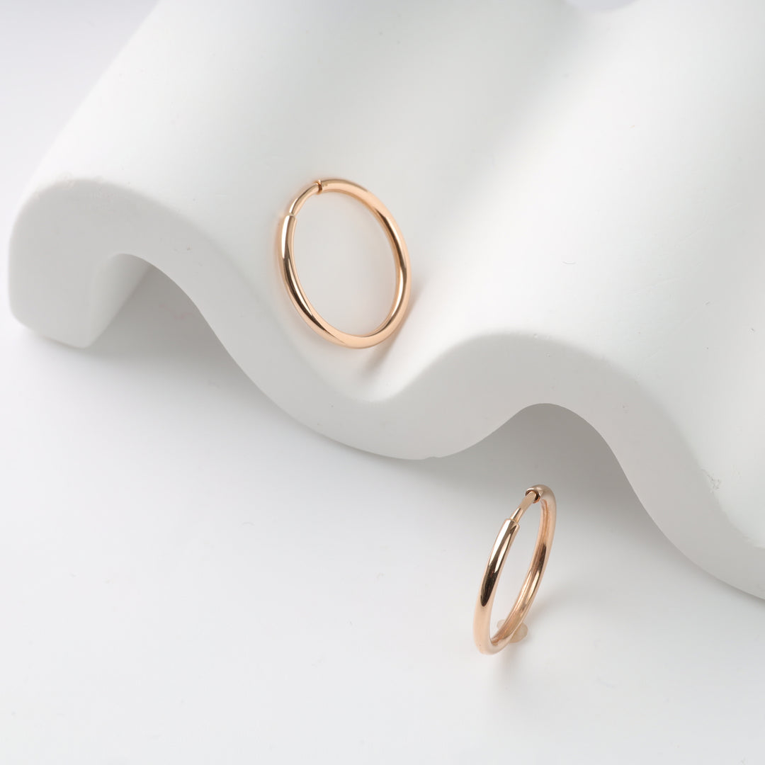 Rose gold hoop earrings displayed on a white surface.