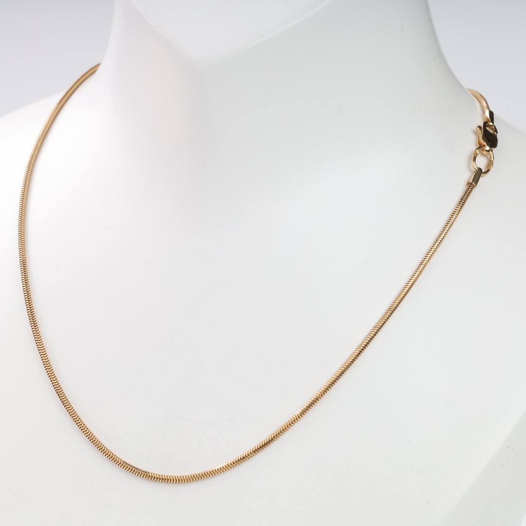 Gold snake chain necklace on a white background.