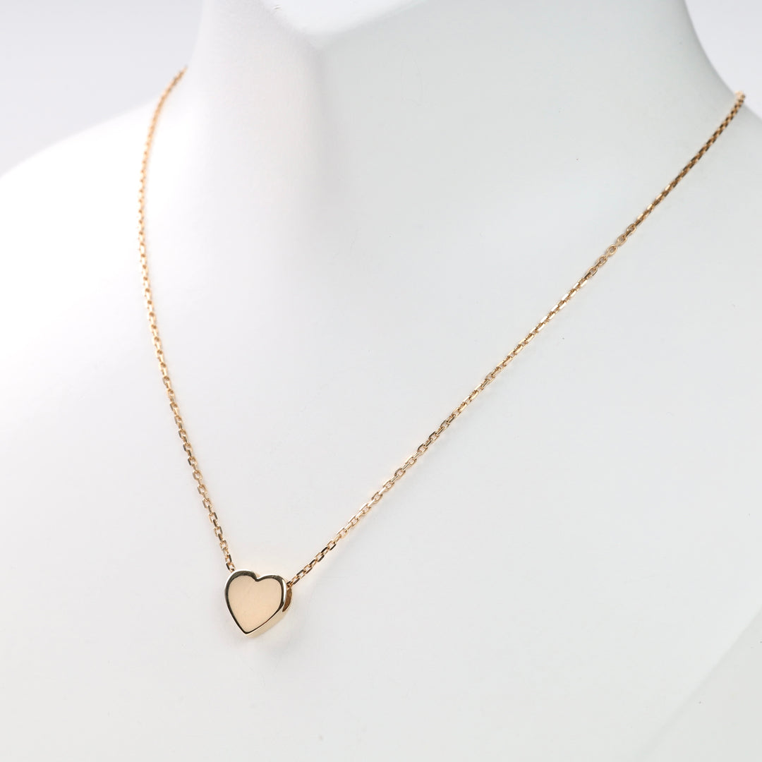 Gold heart pendant necklace on white display bust, single heart on thin gold chain, gold heart necklace, heart pendant, gold chain.