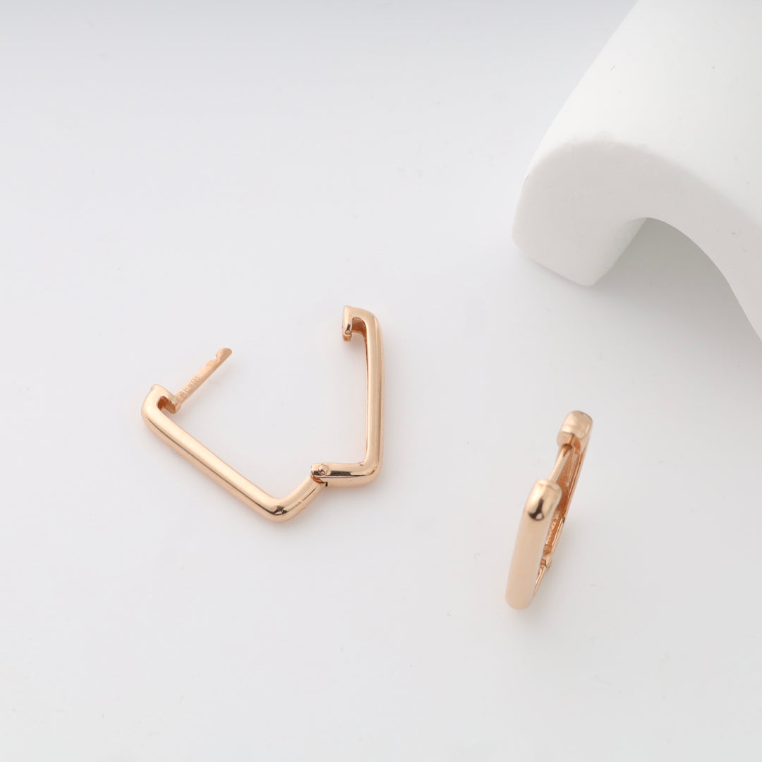 Gold geometric hoop earrings shown on a white background.