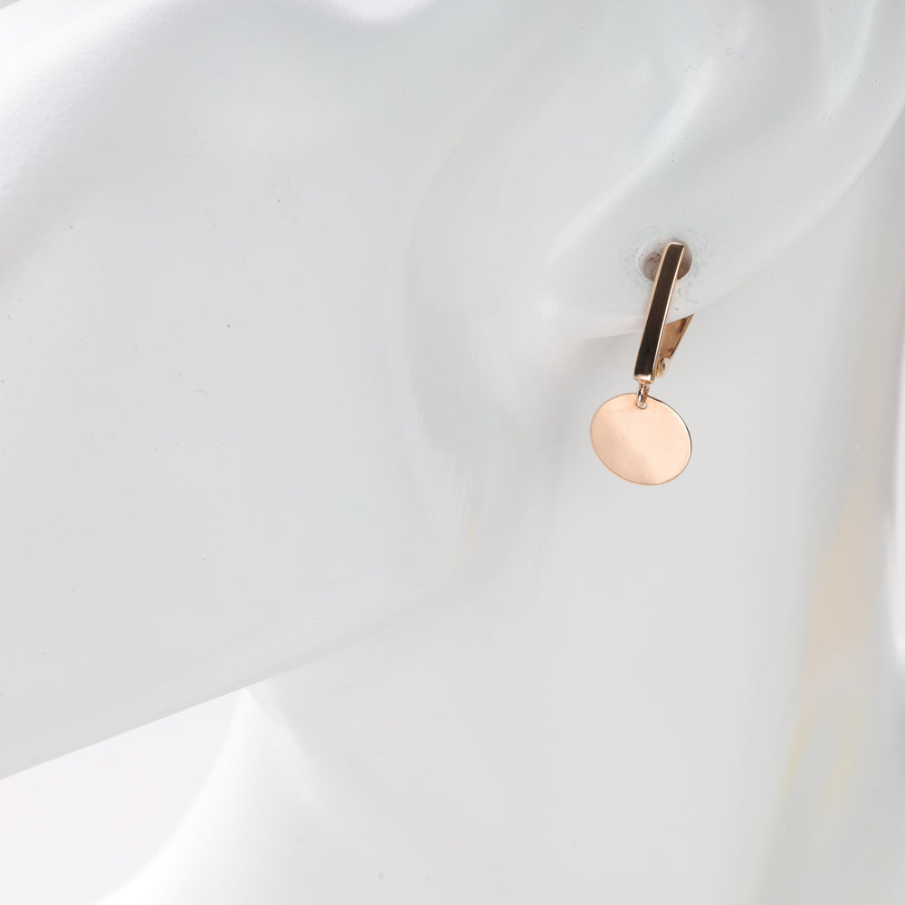 Single gold disc dangle earring displayed on mannequin ear.