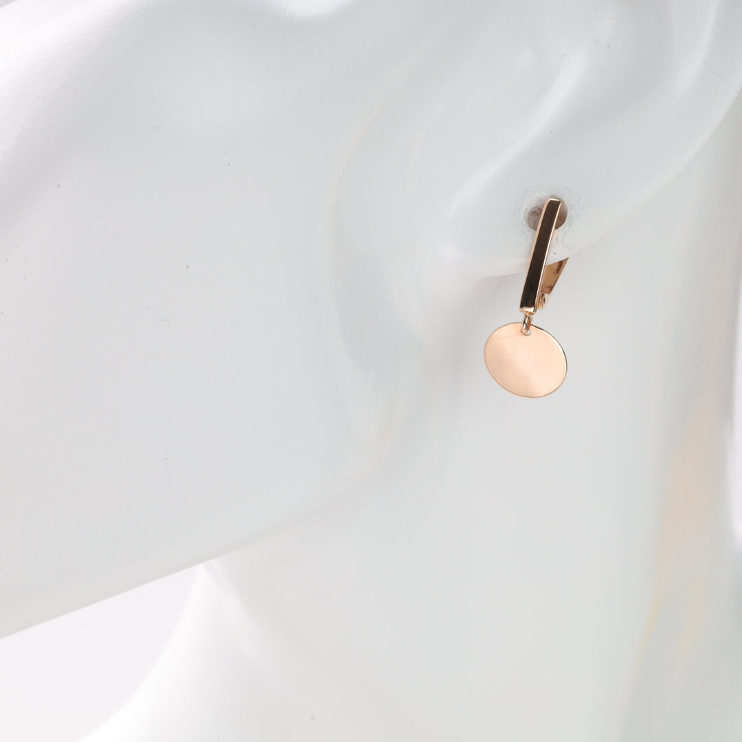 Single gold disc dangle earring displayed on mannequin ear.