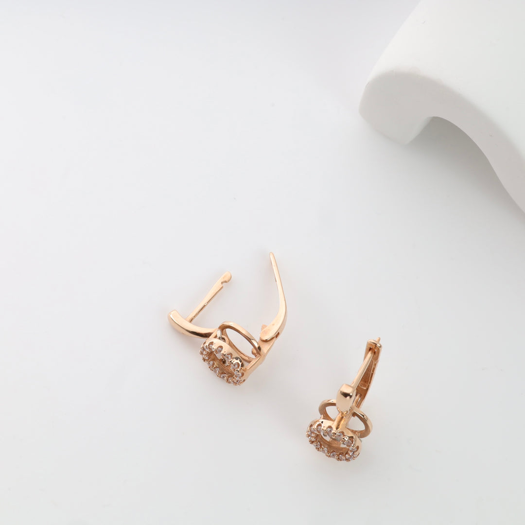 Gold hoop clip-on earrings with crystal accents on a white surface.