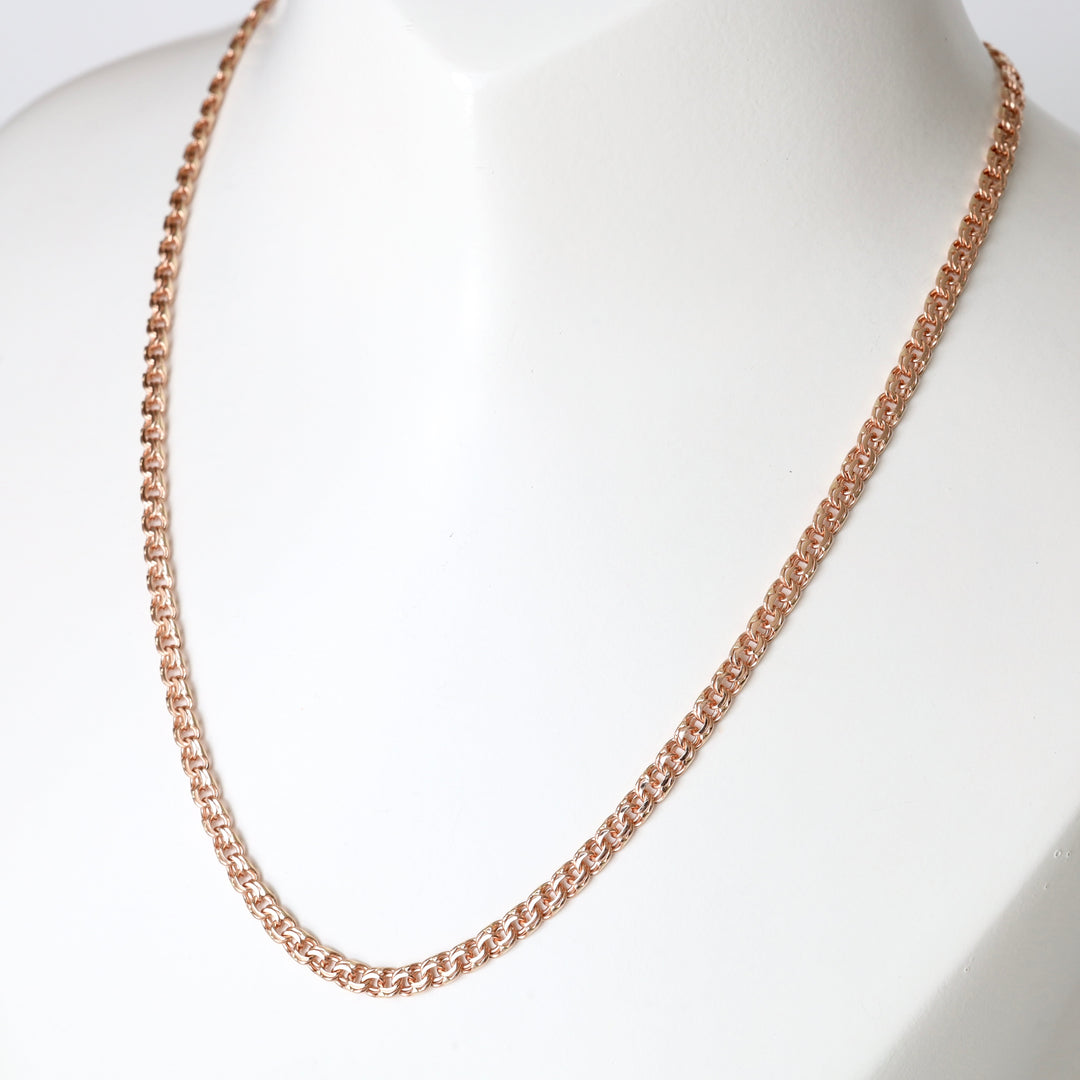 Rose gold chain necklace with intricate round links displayed on a white bust.