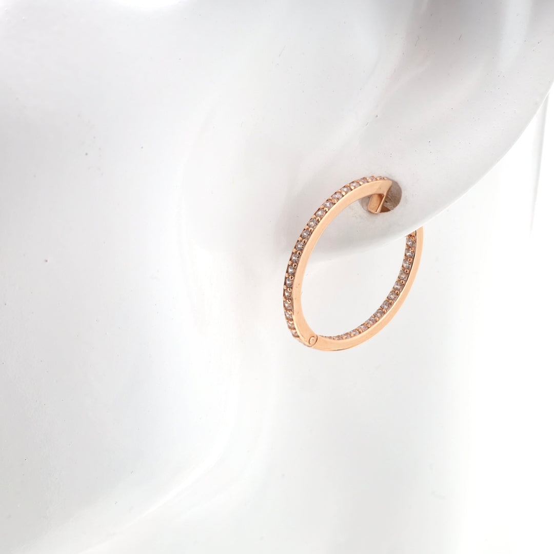 Rose gold hoop earring studded with small crystals displayed on a mannequin.