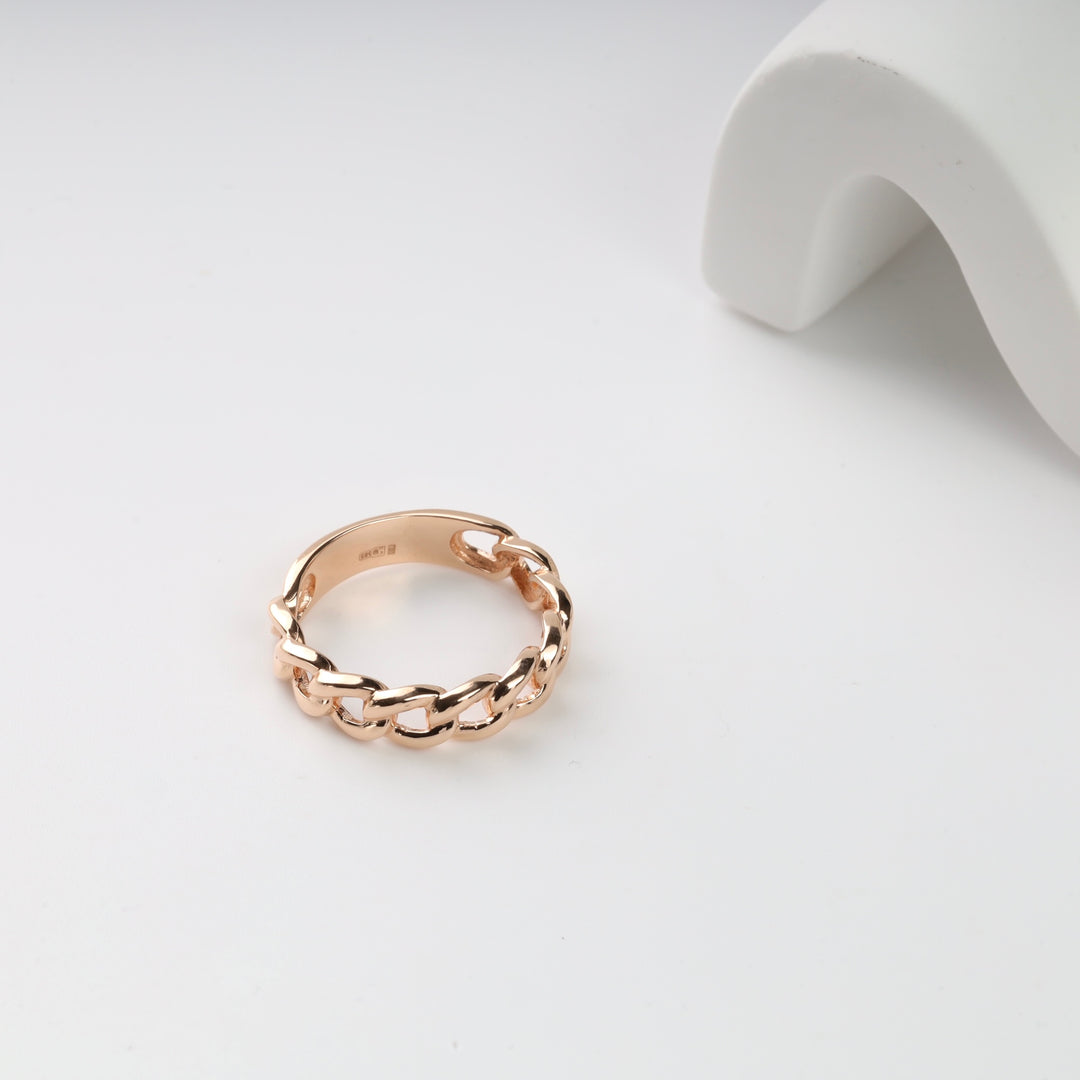 Gold chain link ring on a white surface.