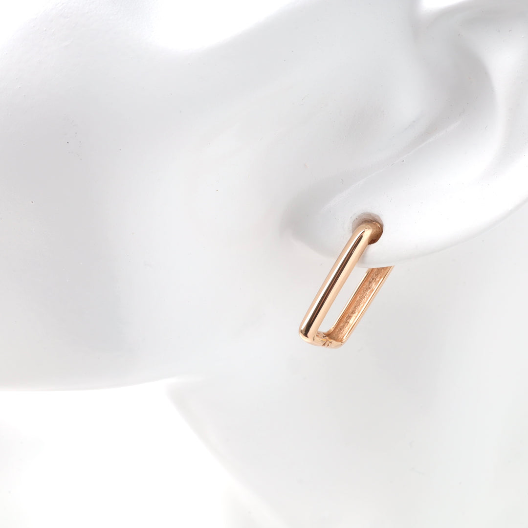 Gold rectangular hoop earring on ear display mannequin.