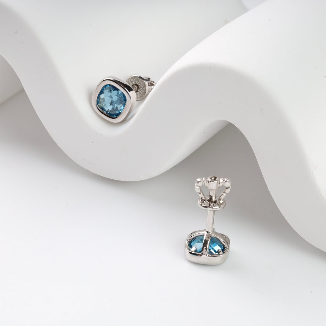 Silver and blue topaz stud earrings displayed on a white surface.