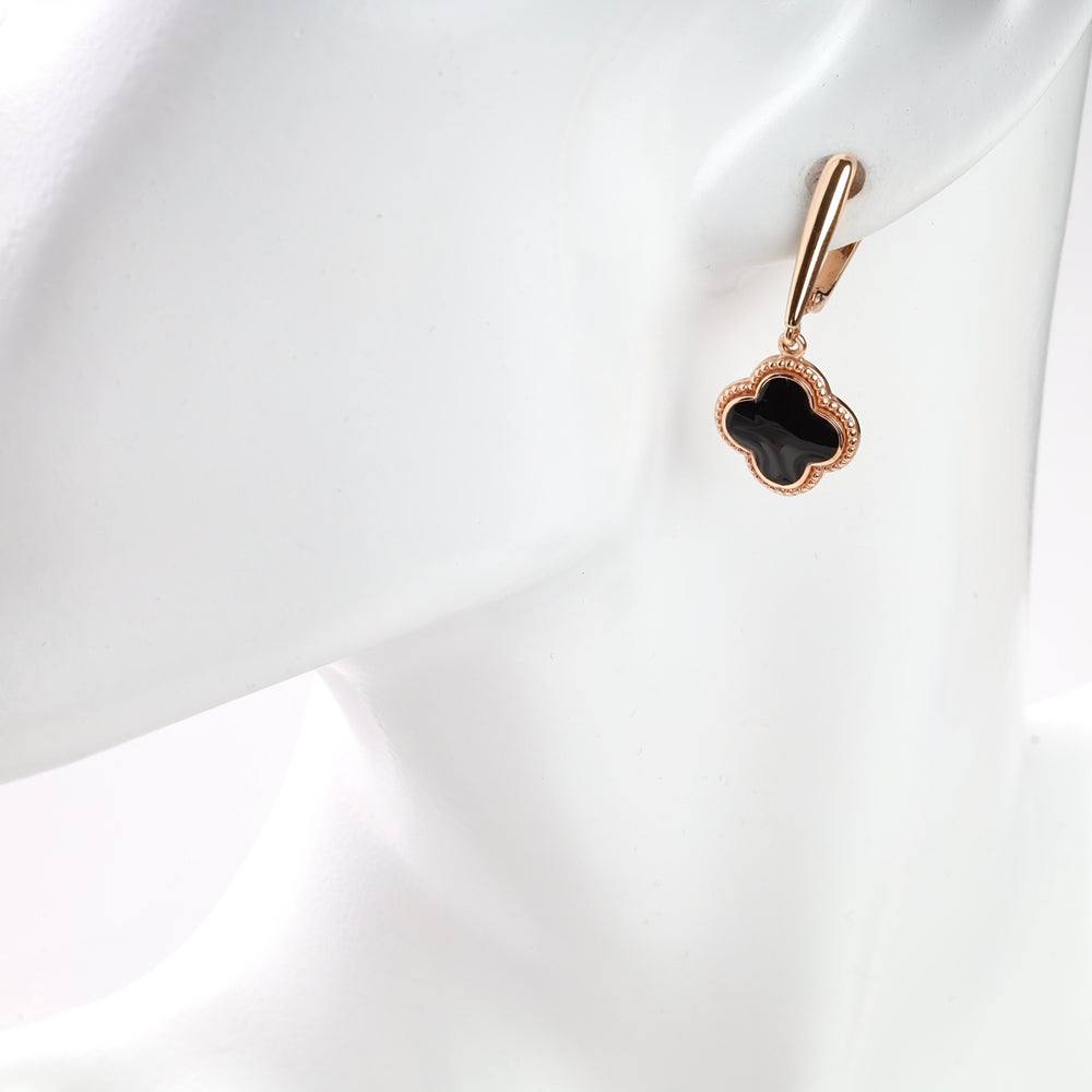 Black enamel clover earring with gold trim on a mannequin.