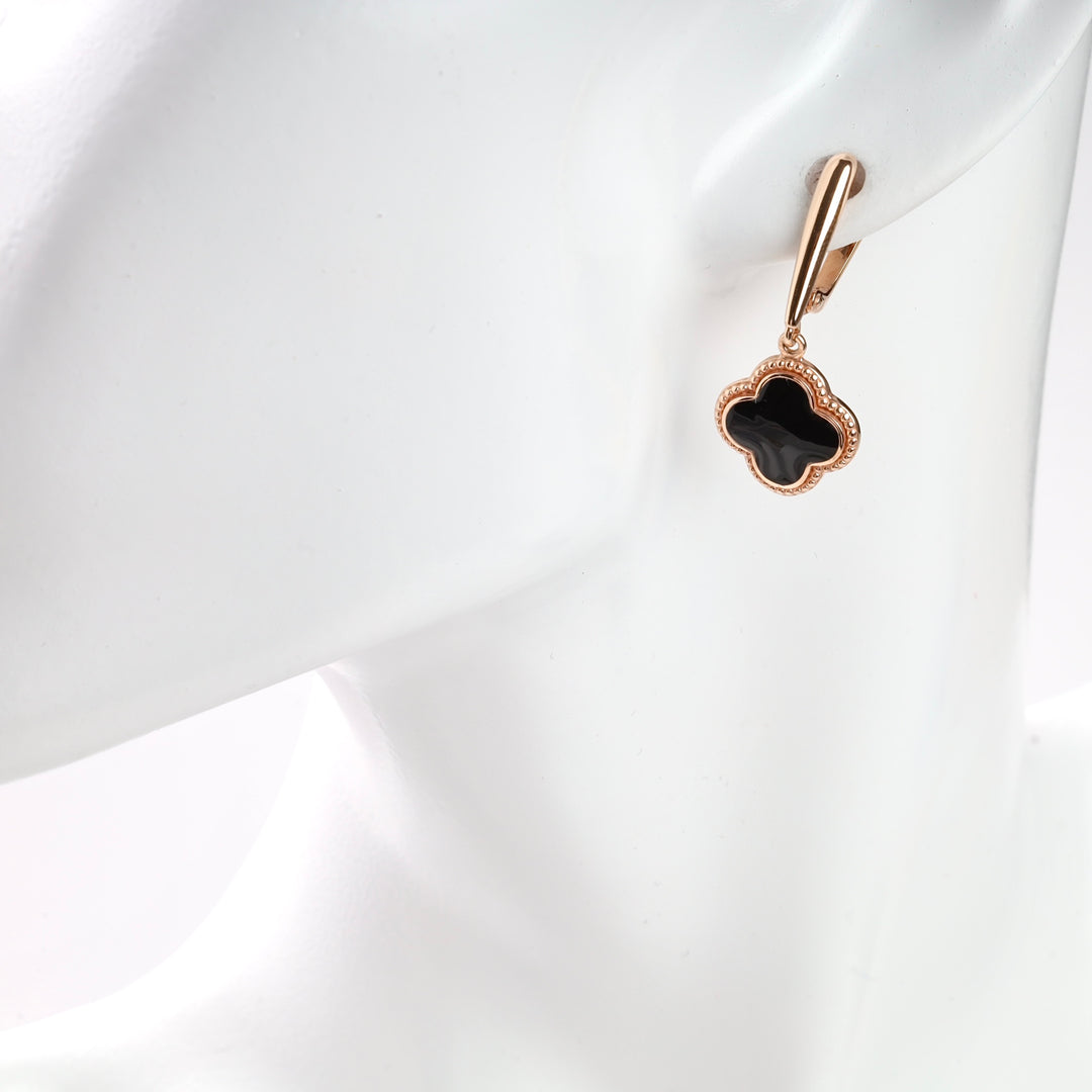 Black enamel clover earring with gold trim on a mannequin.