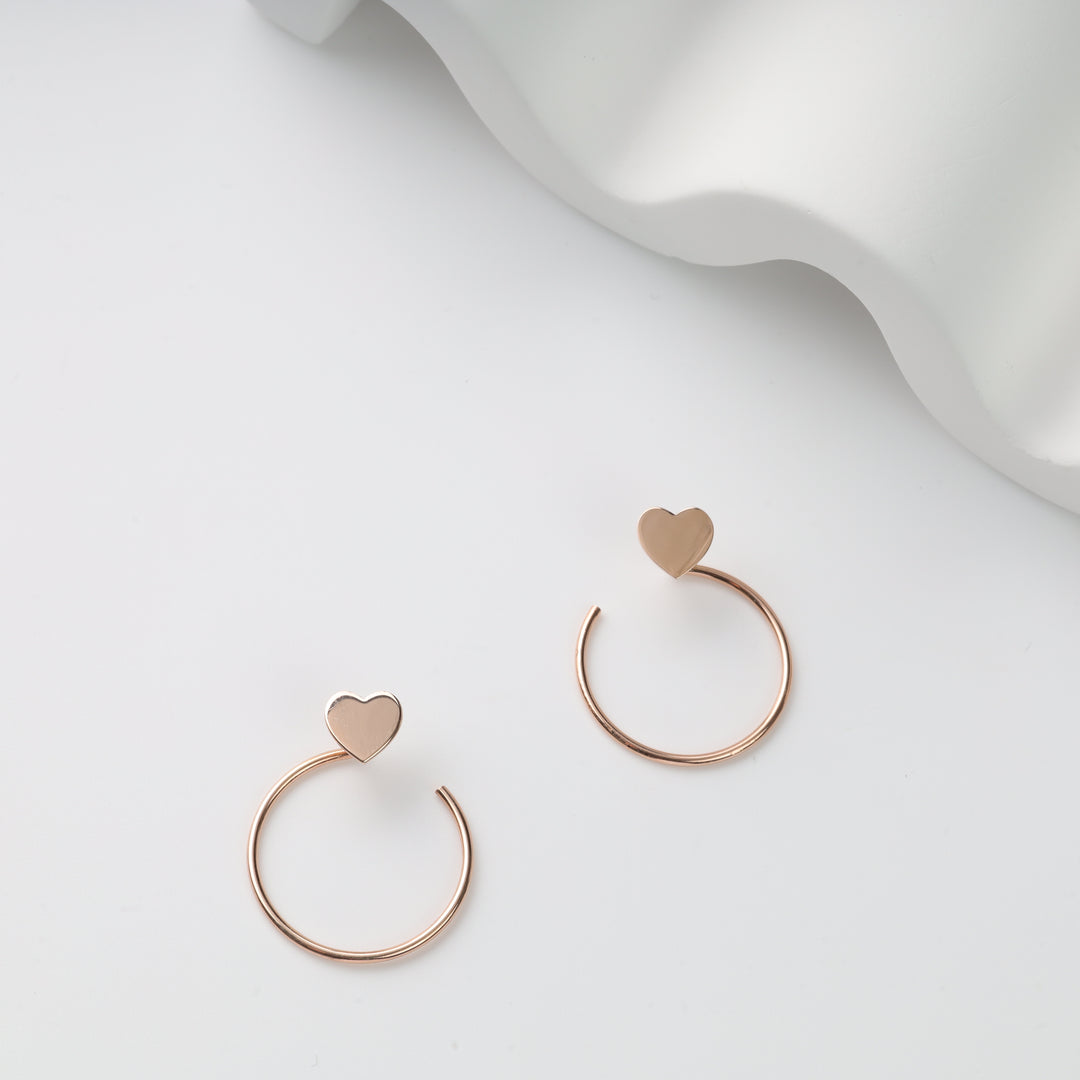 Pair of rose gold open hoop earrings with flat heart tops on white background, rose gold heart hoop earrings, heart stud hoops.