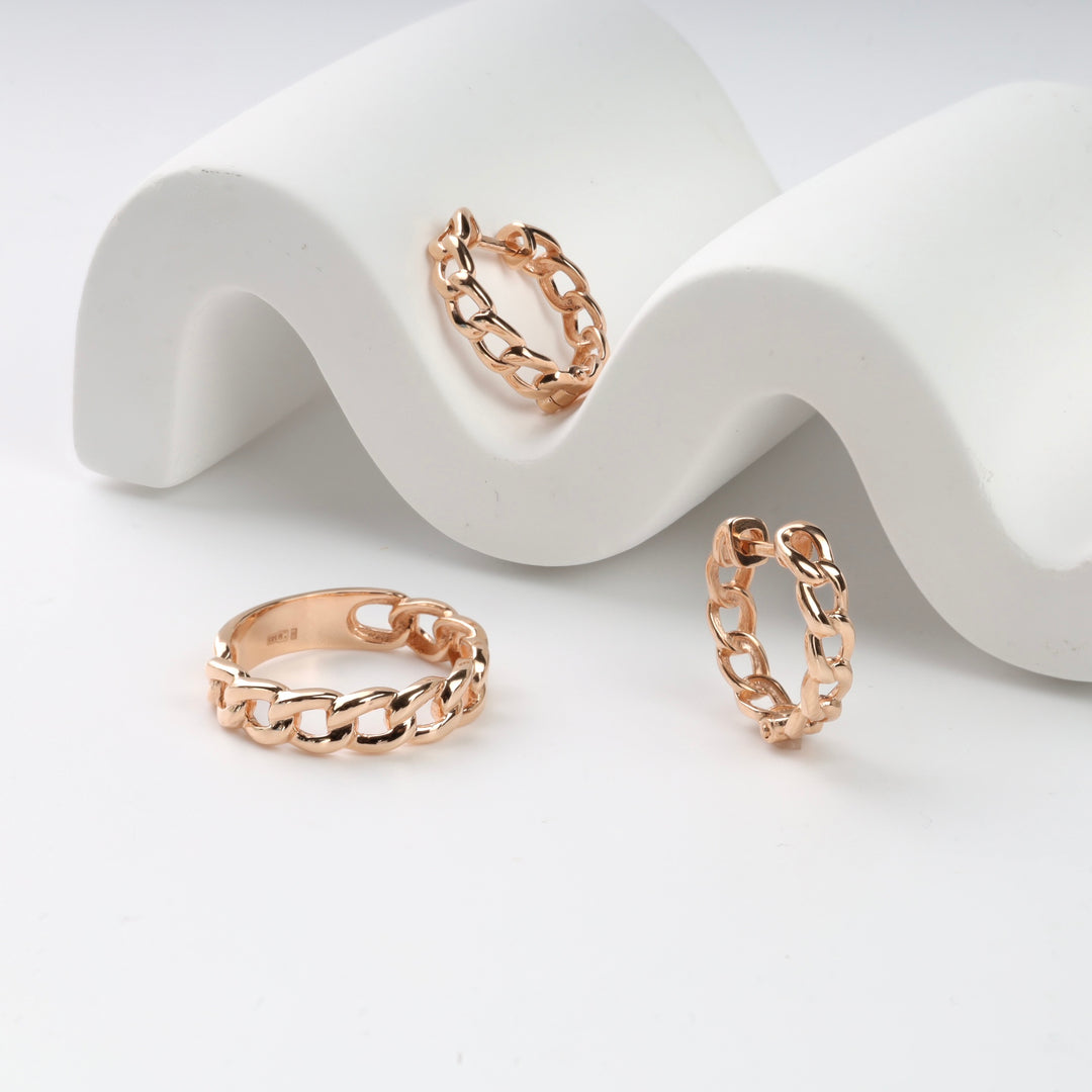 Rose gold chain rings and earrings on a white wave display.